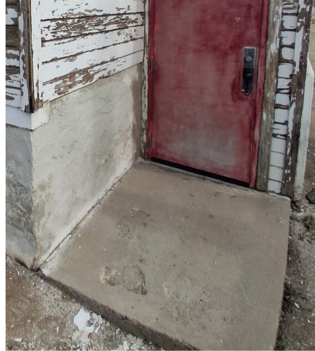 Close-up of a faded red door surrounded by peeling paint