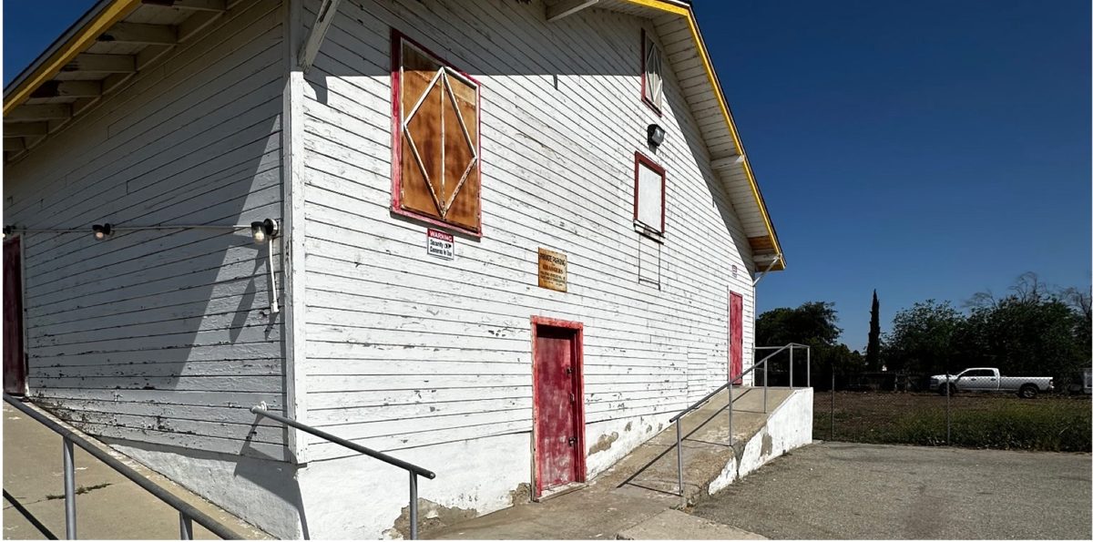 Side wall of a hall with peeling white paint and worn red doors