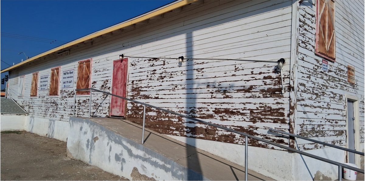 Long wall with large patches of peeling paint and boarded windows